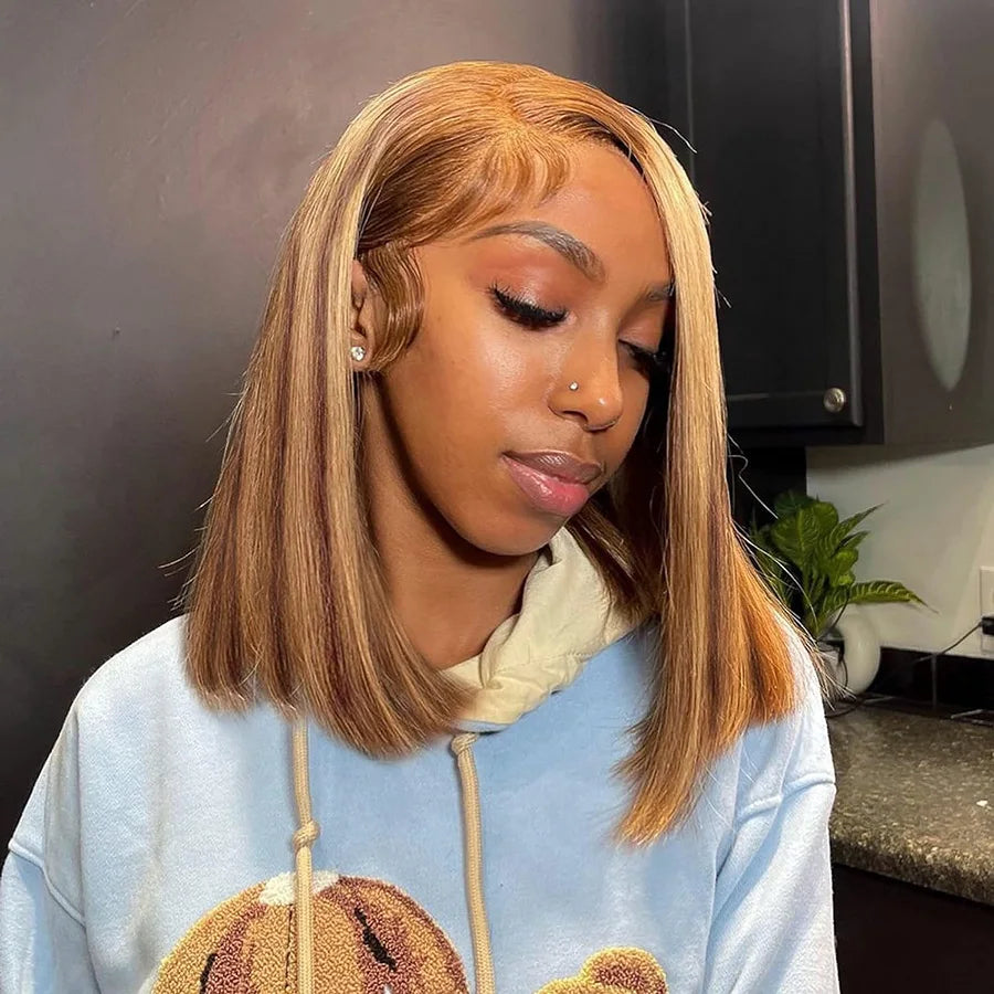 Model wearing a shoulder-length brown bob with honey blonde highlights, a side part and styled baby hairs.